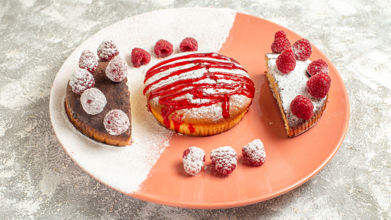 Десерт с ягодами малины и сахарной пудрой на большой тарелке