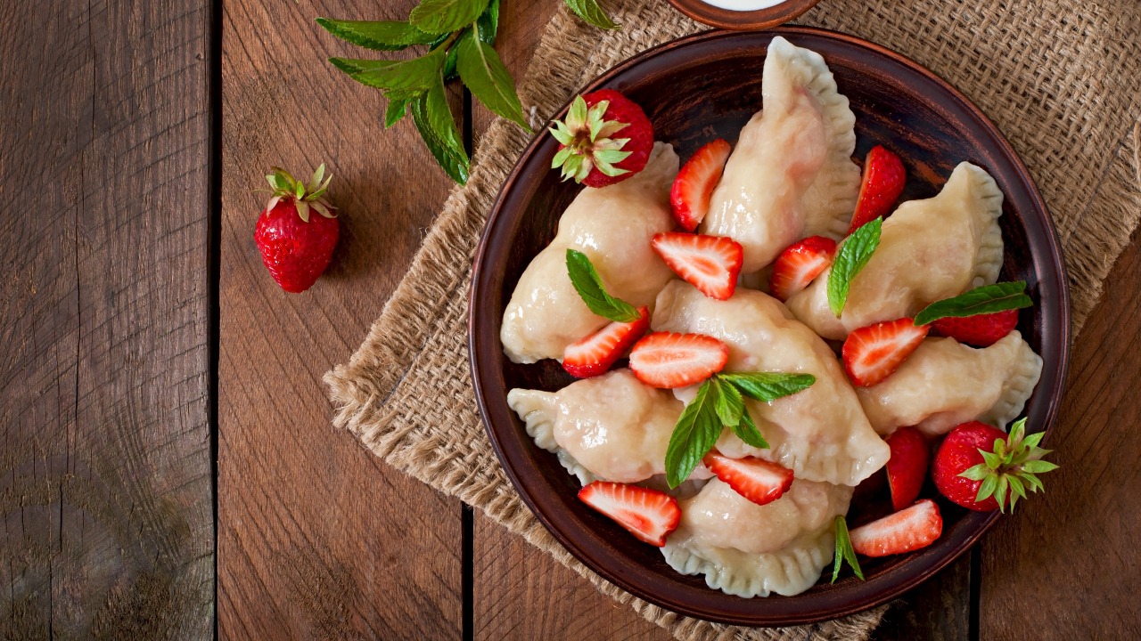 Вареники с клубникой на столе со сметаной