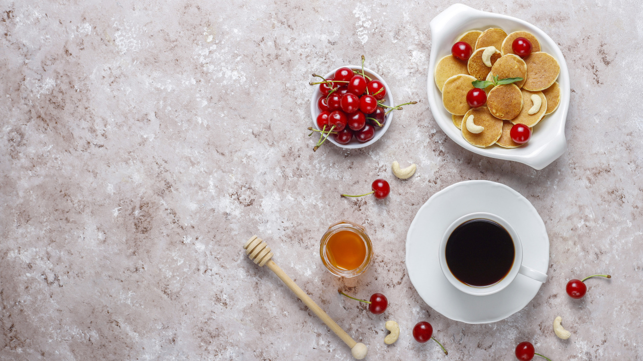 Оладьи на столе с вишней, кофе и медом