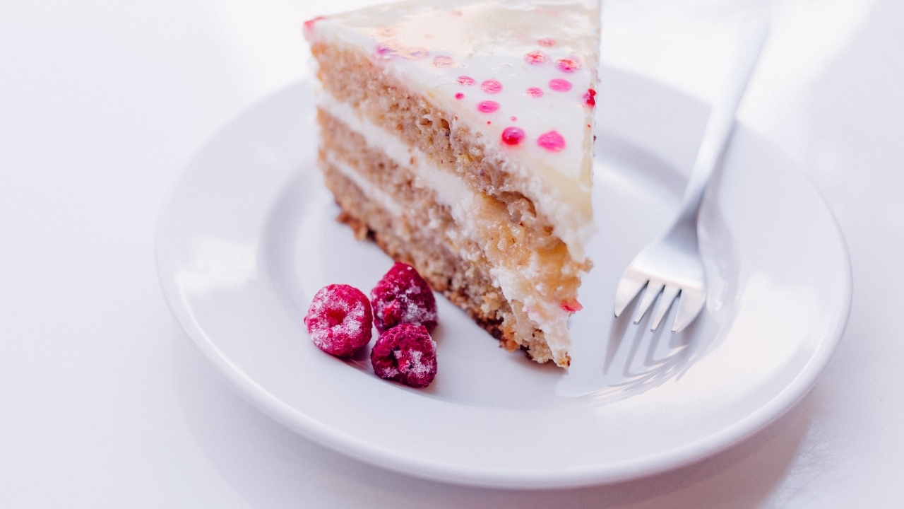 Кусок торта с замороженной малиной на белой тарелке