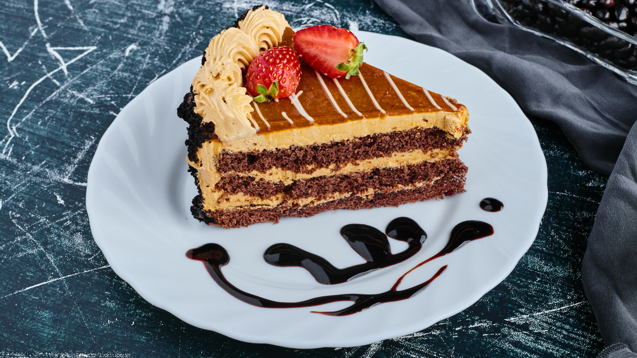 Кусок торта с клубникой на большой белой тарелке