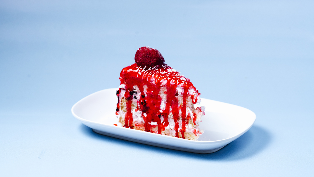 Кусок торта с клубничным сиропом на голубом фоне