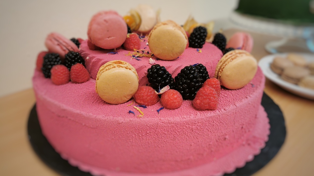 Розовый торт украшен печеньем и ягодами