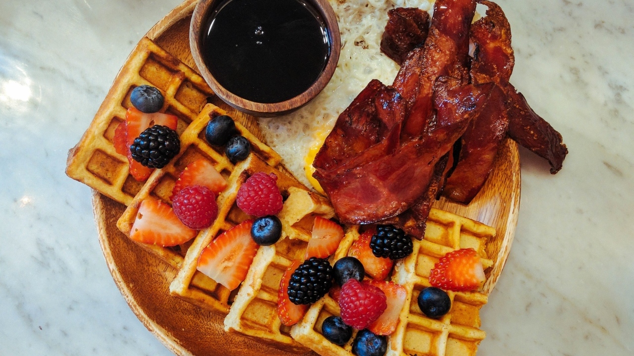 Сладкие вафли с ягодами на тарелке с беконом