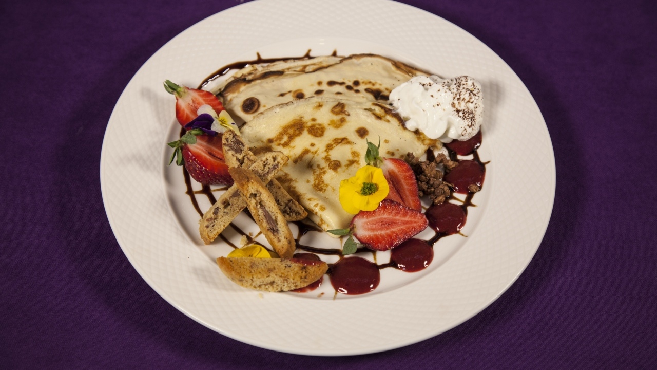 Тонкие блинчики с кремом и ягодами на тарелке