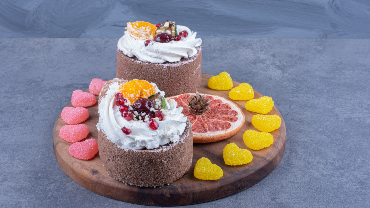 Два пирожных на деревянной доске с мармеладными конфетами