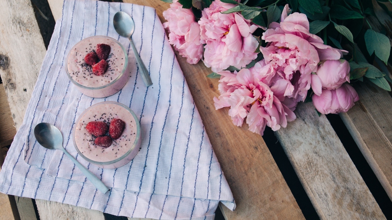 Два стакана с десертом на лавке с букетом пионов