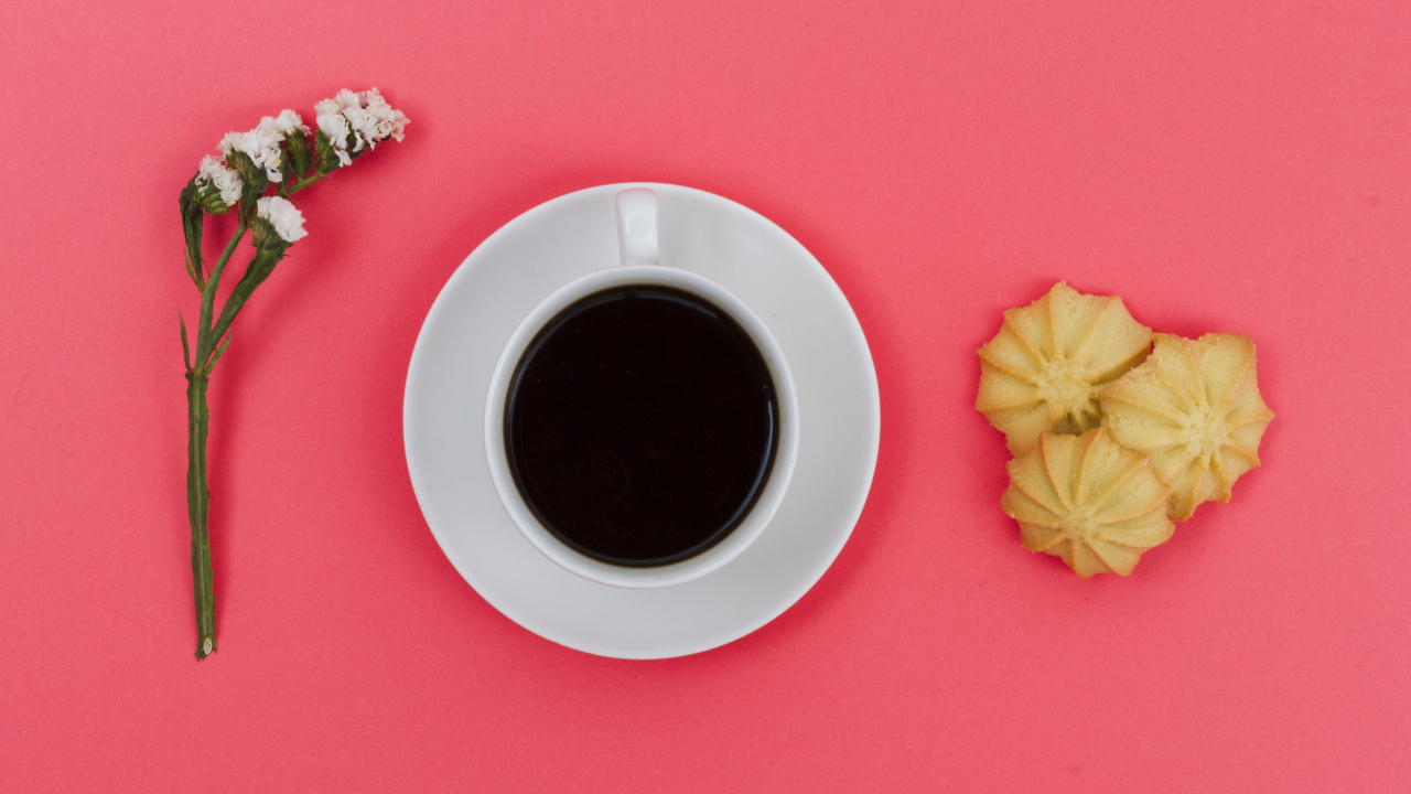 Чашка кофе на розовом фоне с цветком и печеньем