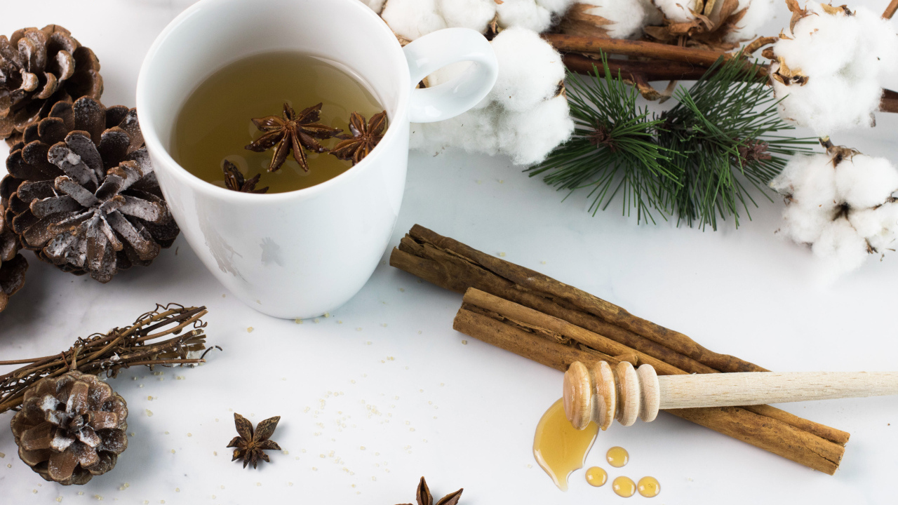 Чашка чая со специями на столе с хлопком и шишками