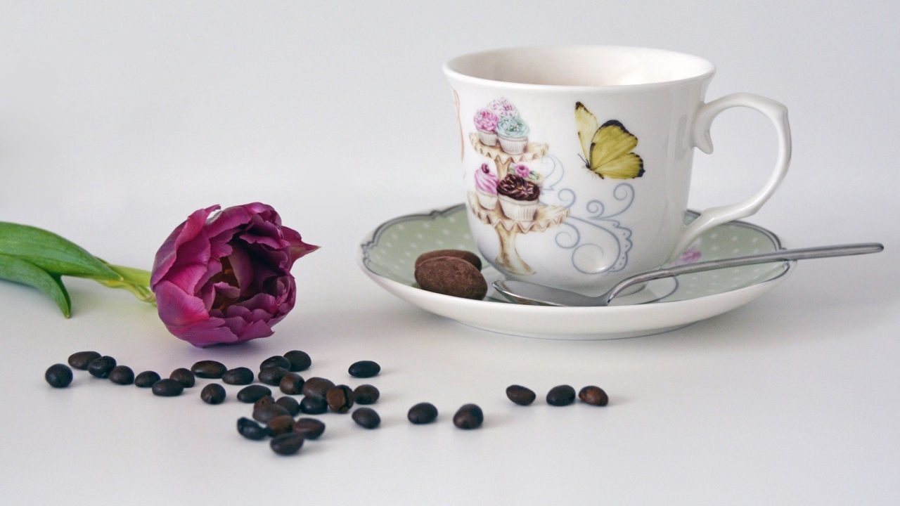 Чашка на столе с кофейными зернами и тюльпаном