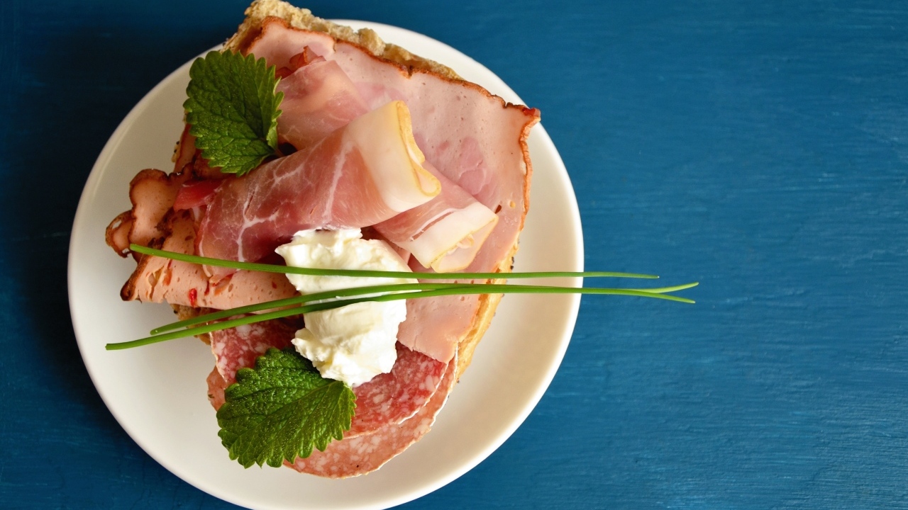 Бутерброд с колбасой и беконом на синем столе