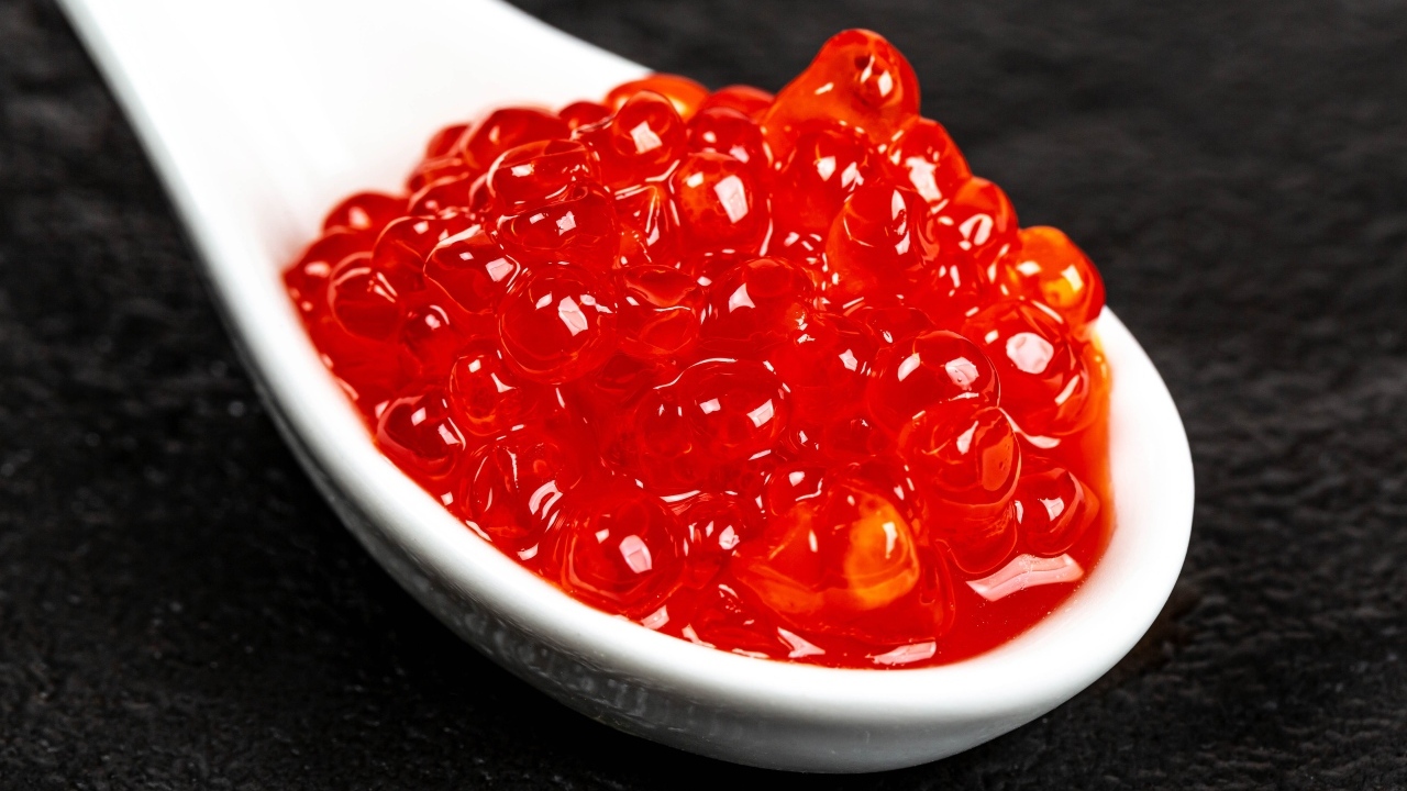 Красная икра на белой ложке крупным планом