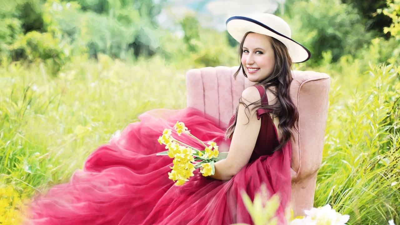 Красивая девушка в розовом платье сидит на кресле в траве