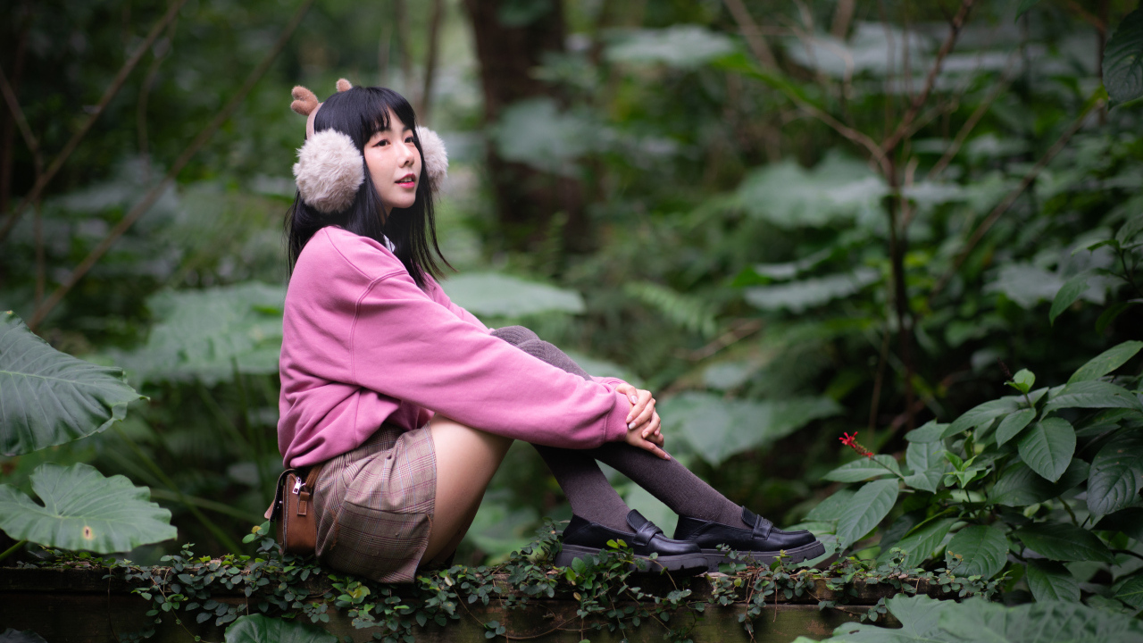 Девушка азиатка в розовом наряде сидит в зарослях