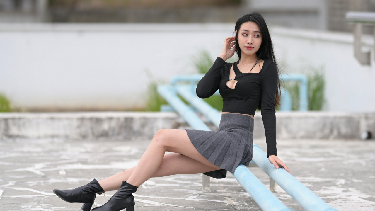 Азиатка в короткой юбке сидит на трубе