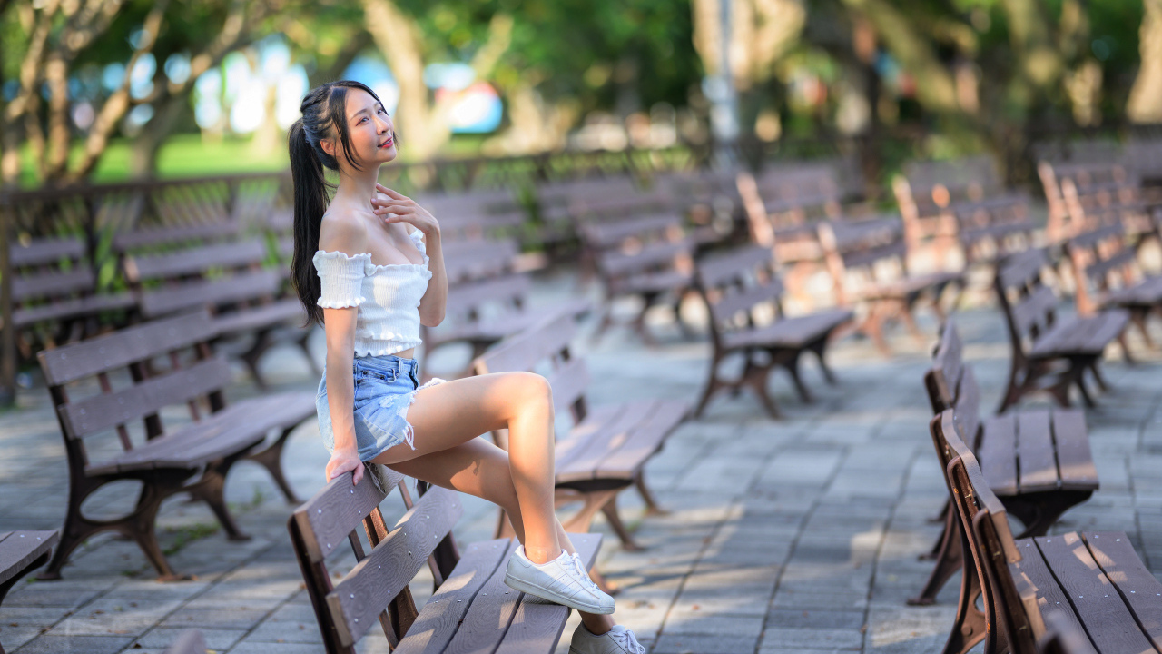 Спортивная азиатка сидит на лавке в парке