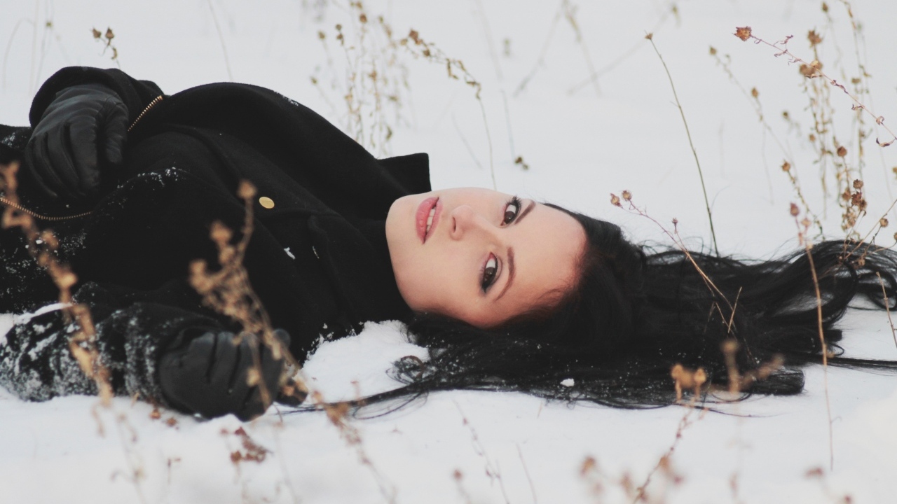 Красивая брюнетка лежит на холодном снегу
