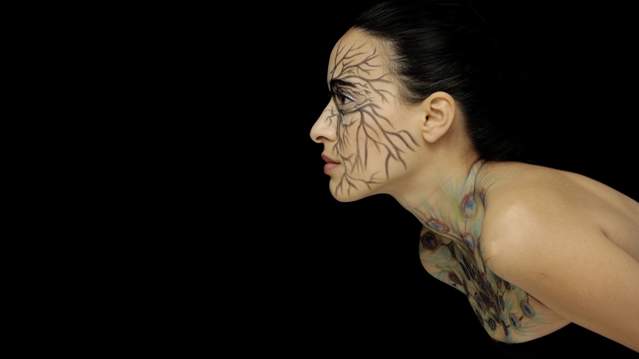 Красивая девушка с рисунком на теле на черном фоне