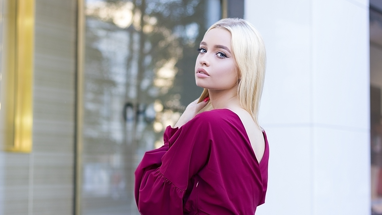 Милая девушка блондинка в платье стоит у здания