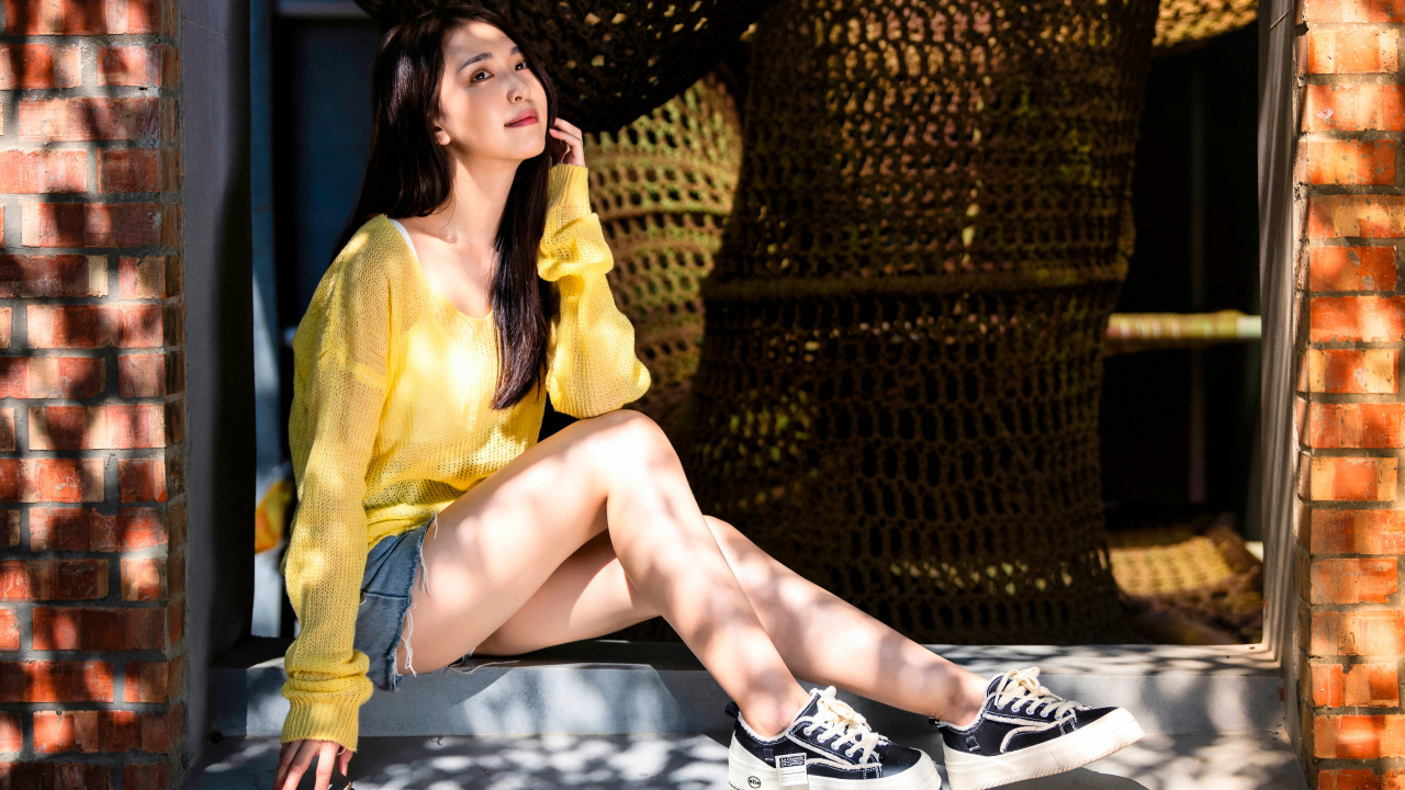 Мечтательная молодая девушка азиатка сидит на окне