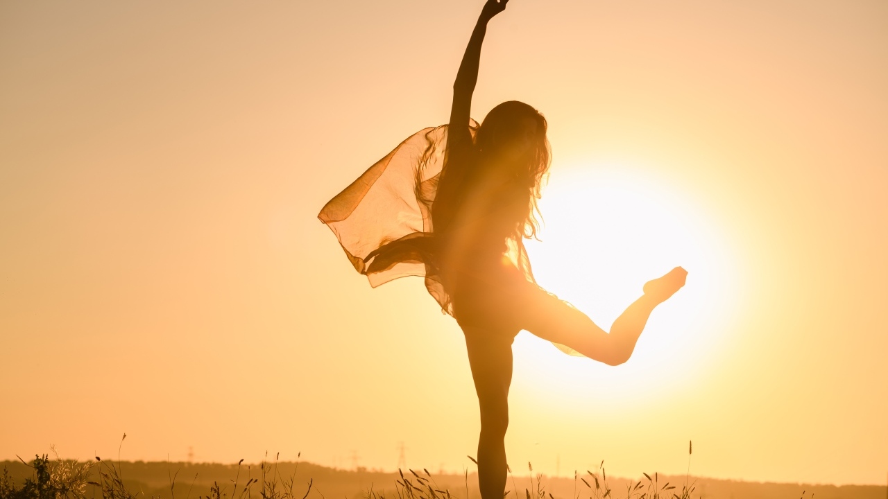 Девушка танцует в лучах солнца на закате