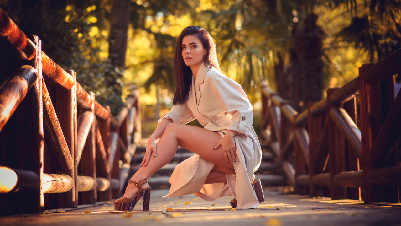 Девушка в пальто на мосту в парке 