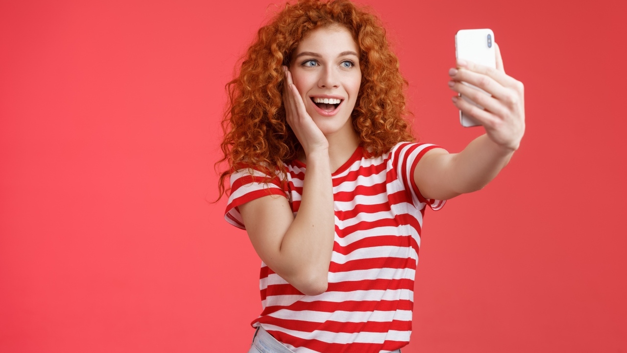 Девушка делает селфи на красном фоне