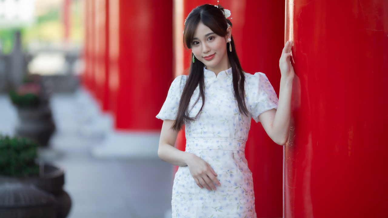 Длинноволосая азиатка позирует у красной колонны