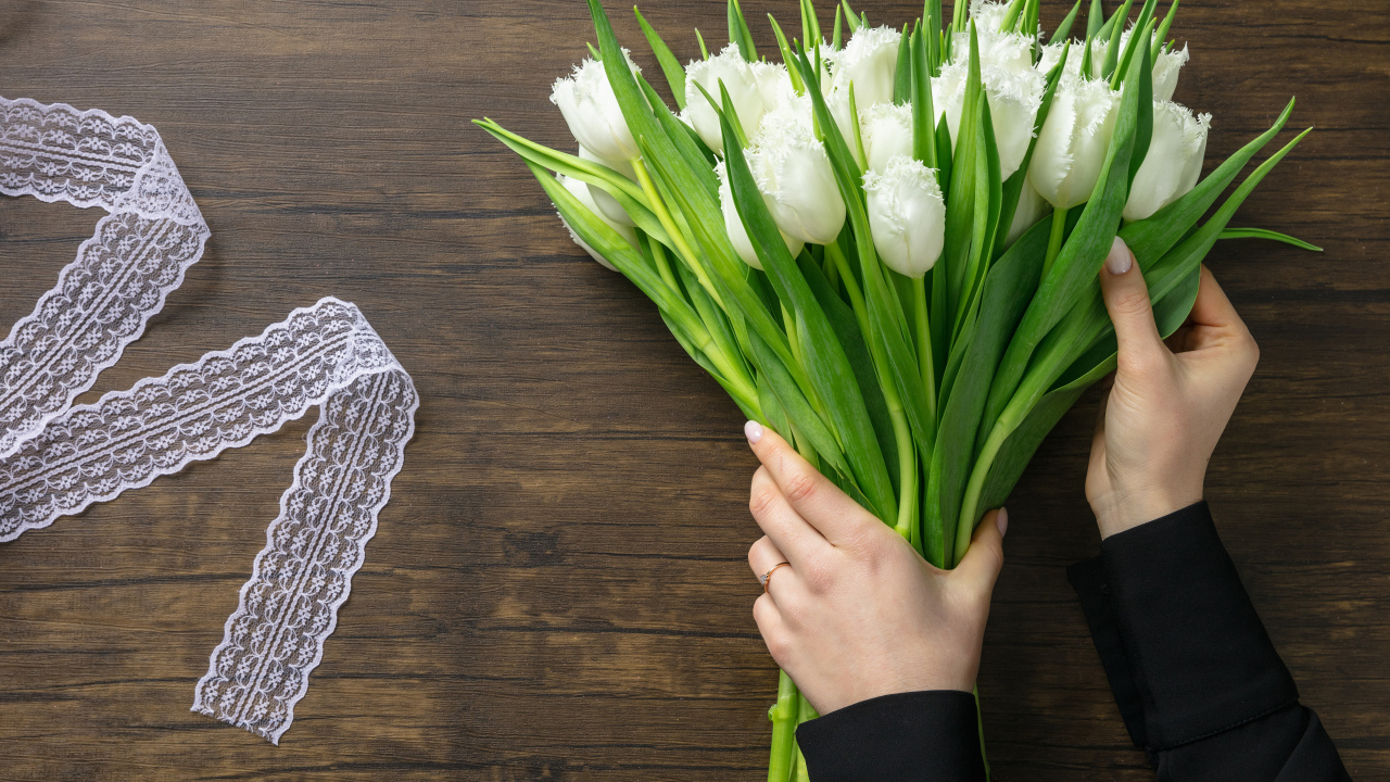 Большой букет белых тюльпанов с лентой на столе на 8 марта