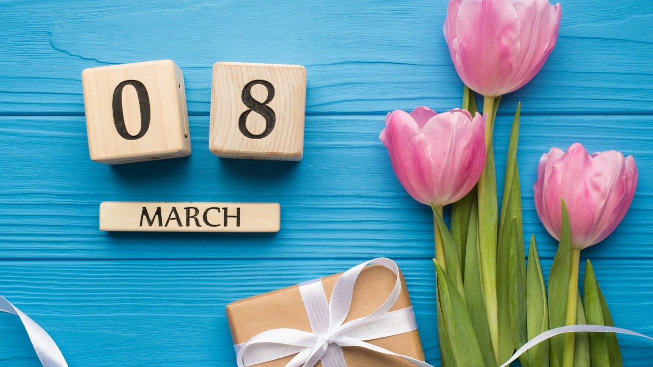 Розовые тюльпаны с подарком и кубиками на голубом фоне на 8 марта