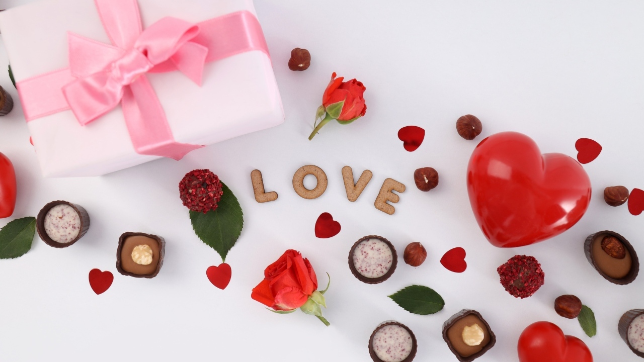 Подарок и сердечки с конфетами на столе на День Святого Валентина