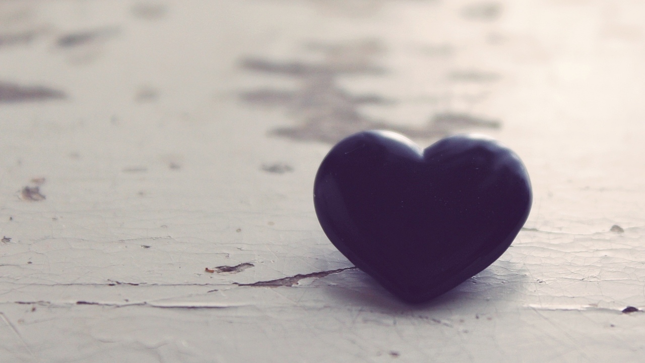 Черное каменное сердце на деревянной поверхности 