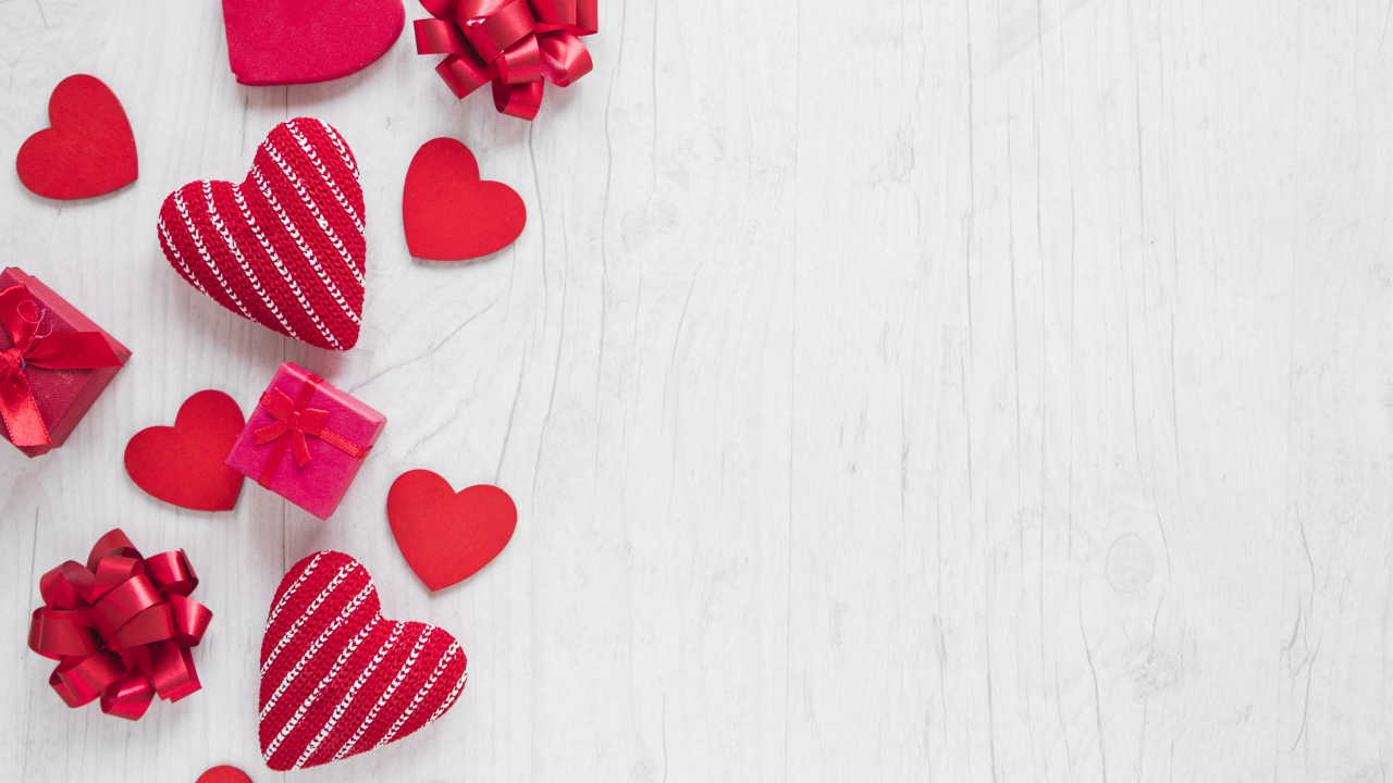 Красные сердечки с подарками и бантами на деревянном фоне