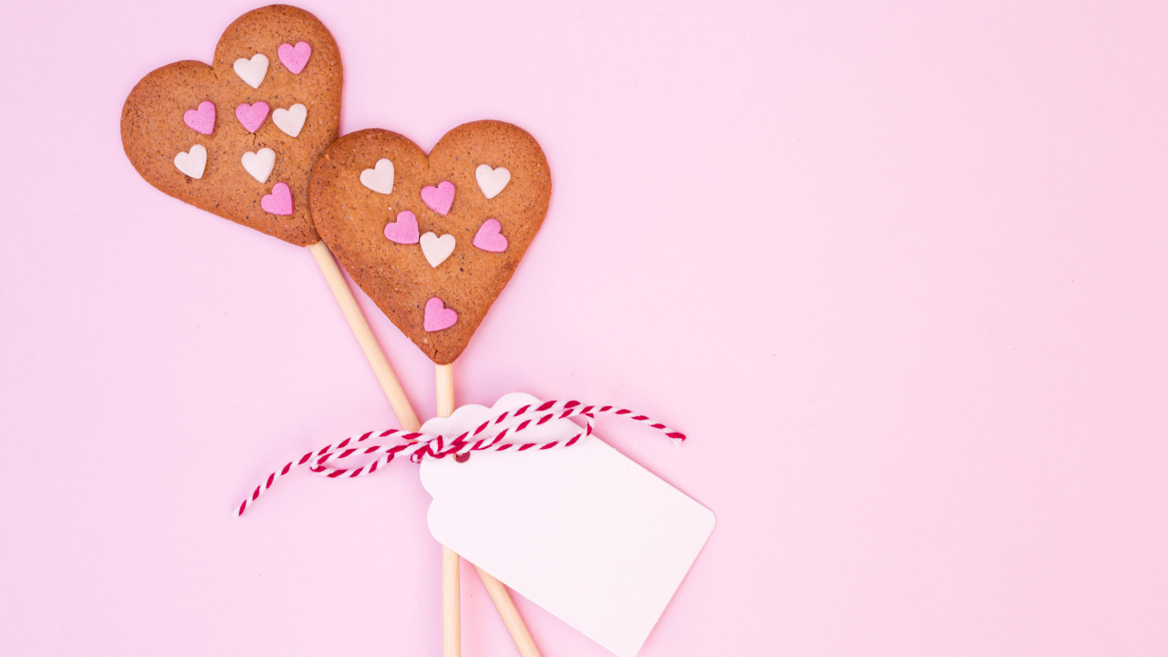Два сердечка на палочке на розовом фоне