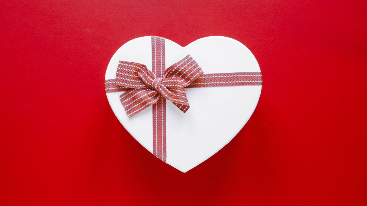 Белая коробка в форме сердца с бантом на красном фоне