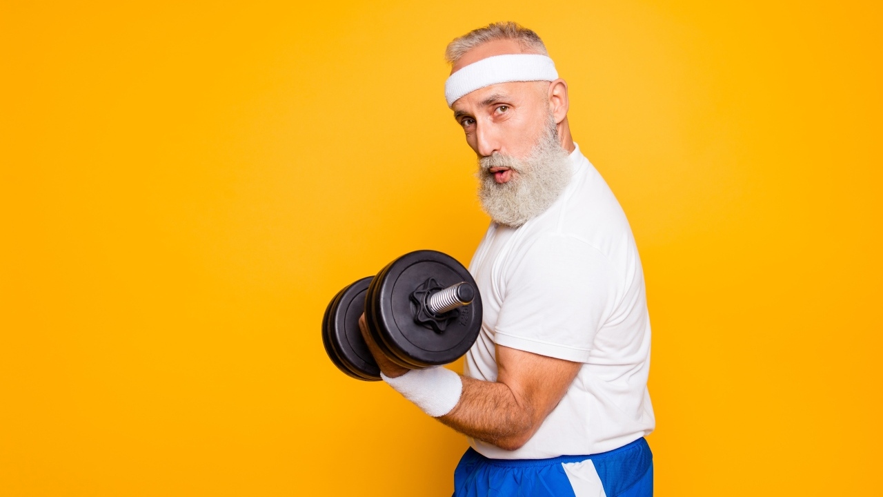 Спортивный мужчина с гантелей в руке на желтом фоне