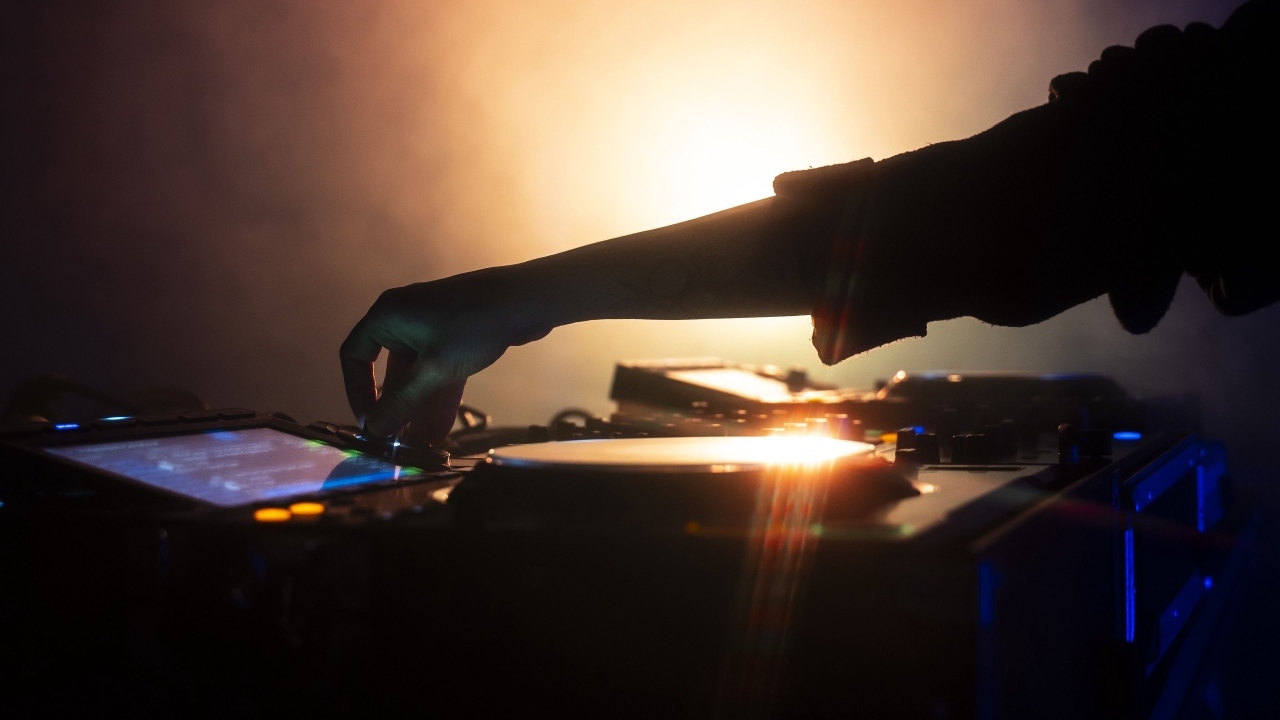 Рука диджея настраивает музыкальный пульт 