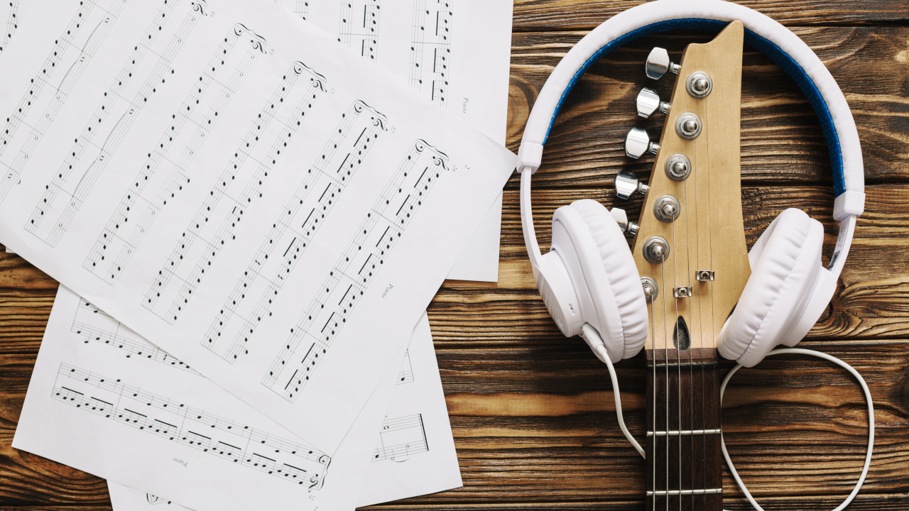 Ноты, наушники и гитара на столе