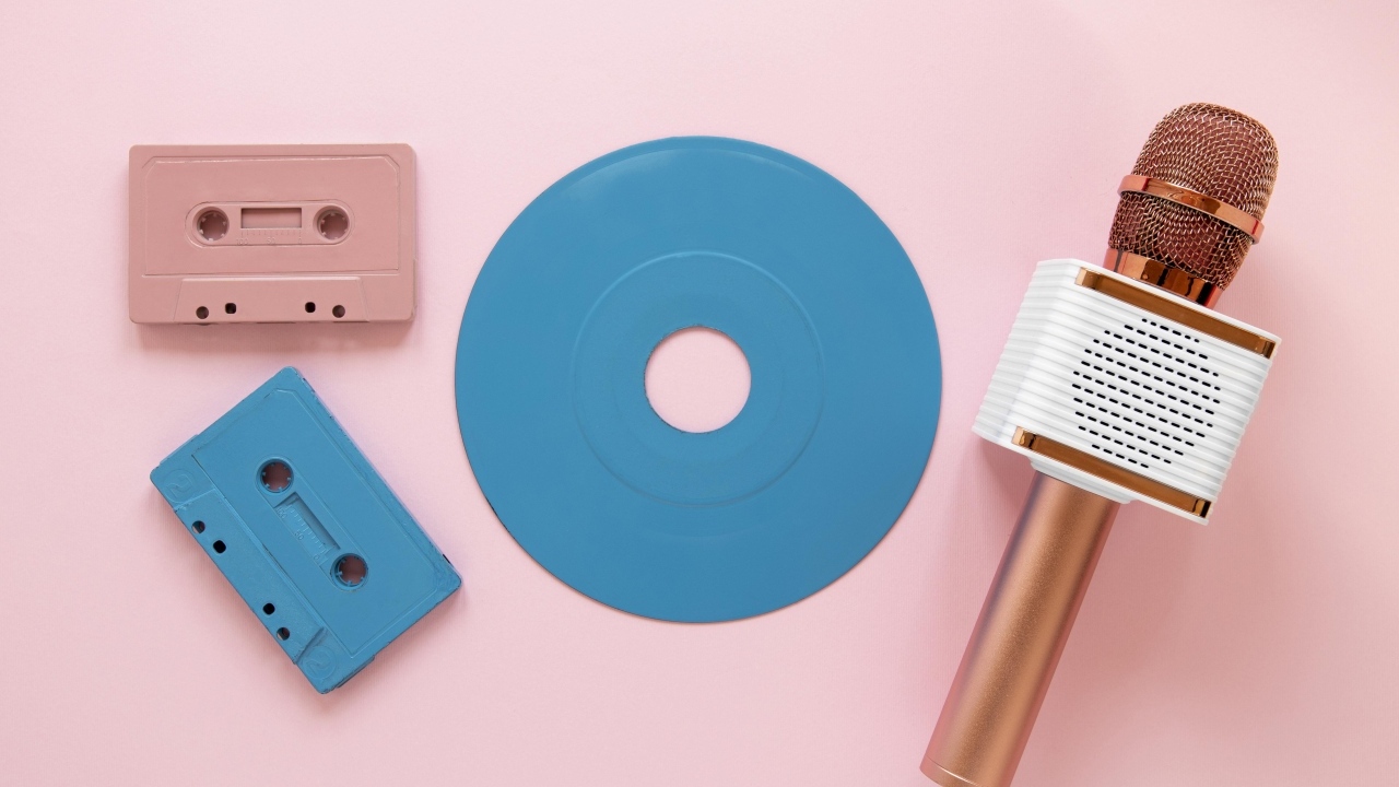 Две кассеты, микрофон и пластинка на розовом фоне