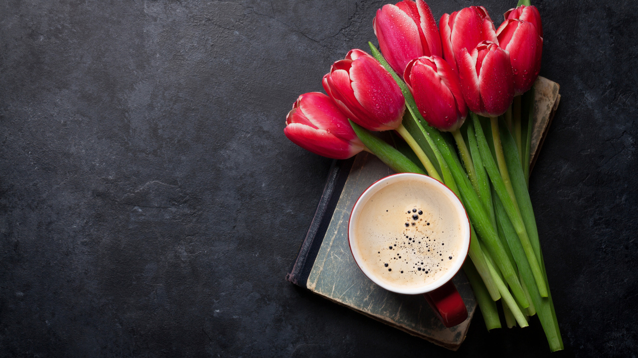 Букет красных тюльпанов с чашкой кофе на черном столе