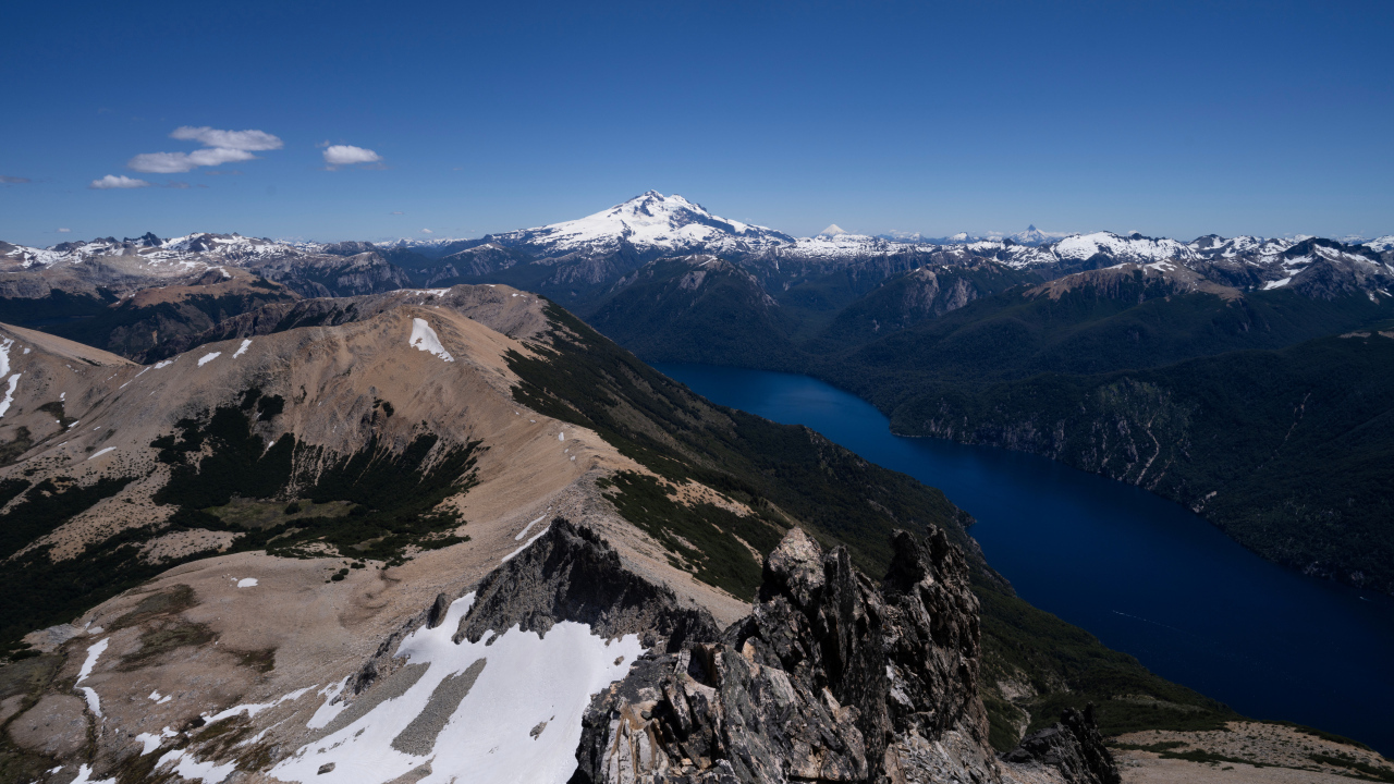 Высокие заснеженные горы и река под голубым небом