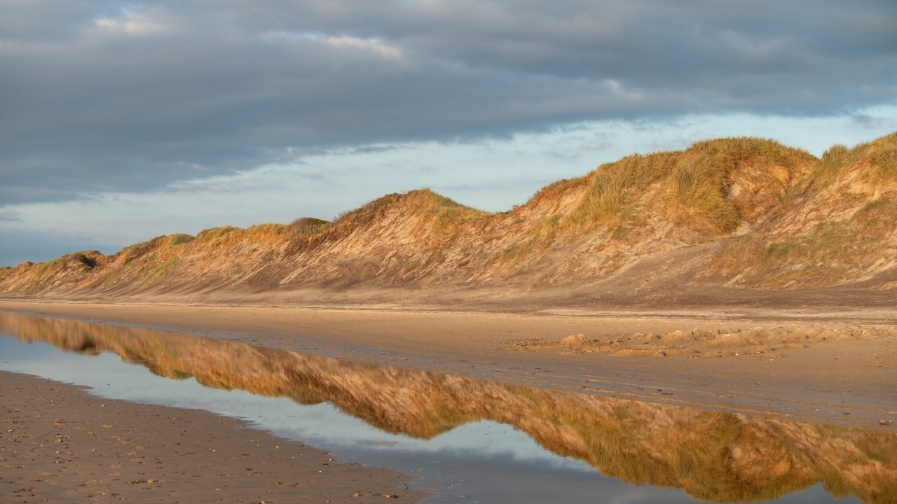 Холты отражаются в реке под грозовым небом