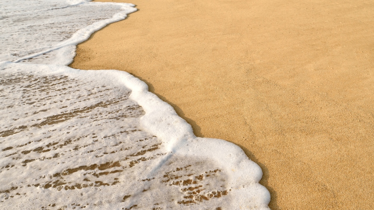 Белая пена на горячем песке на пляже