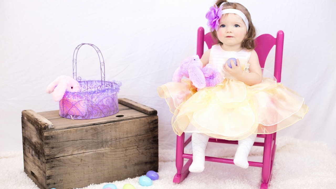 Девочка в красивом платье сидит на стуле 