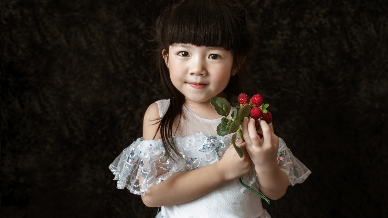 Девочка азиатка в белом платье с ягодами в руке