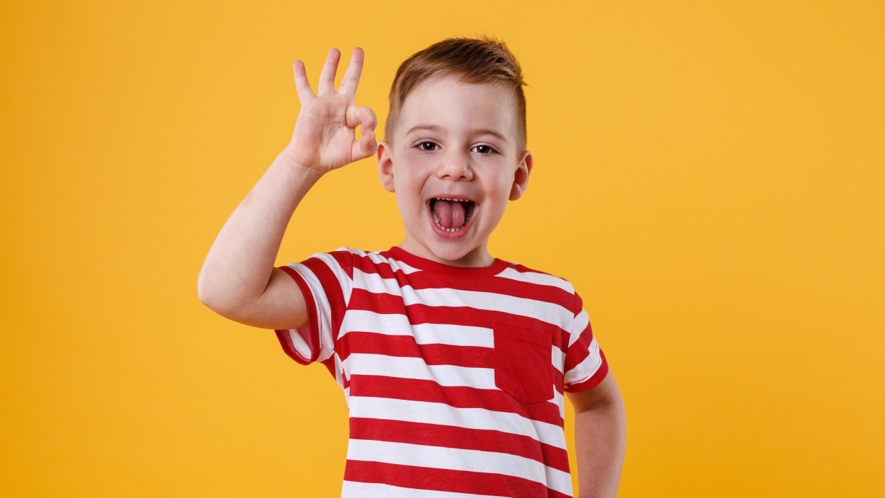 Веселый мальчик в полосатой футболке на оранжевом фоне