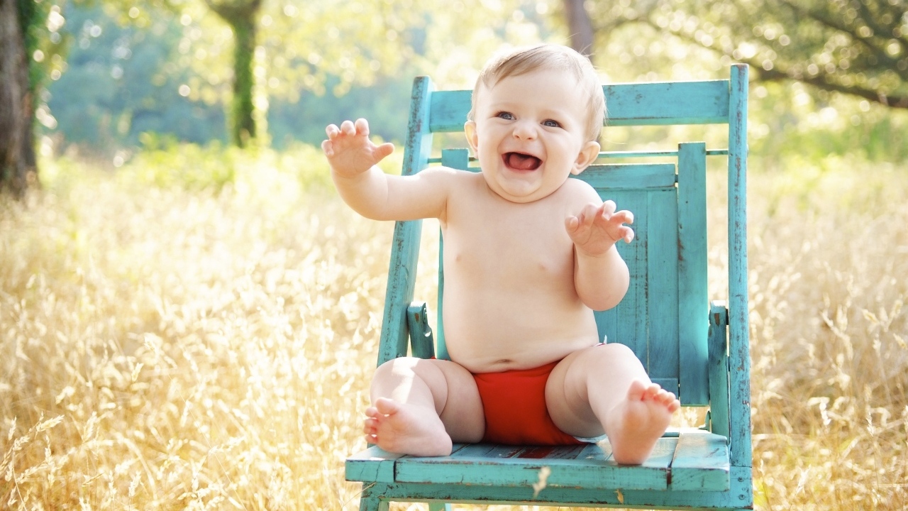 Веселый маленький мальчик в кресле 