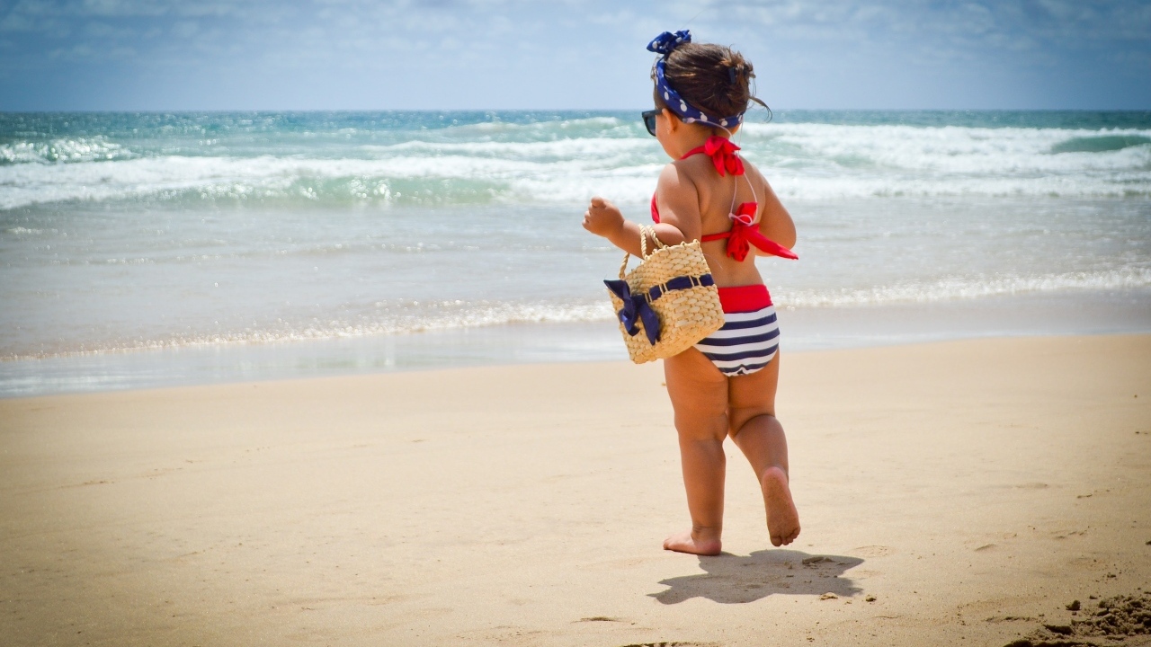 Модная маленькая девочка с сумочкой на берегу моря