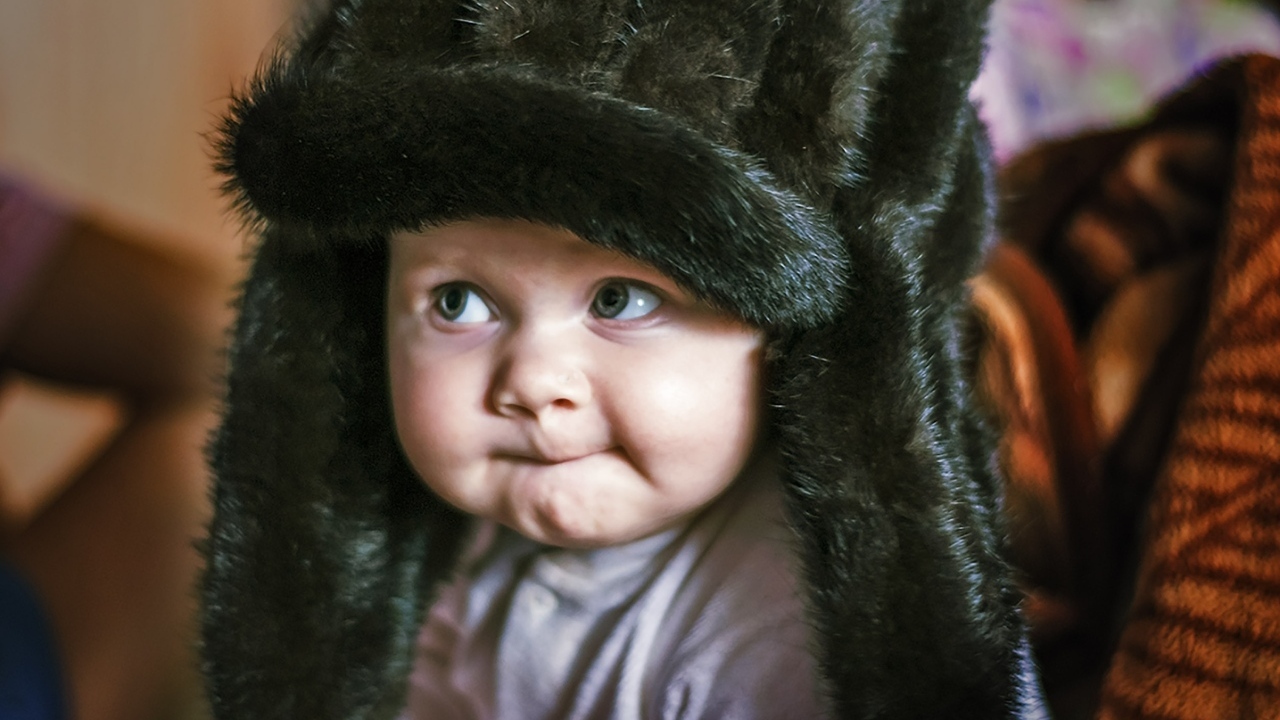 Смешной ребенок в черной меховой шапке