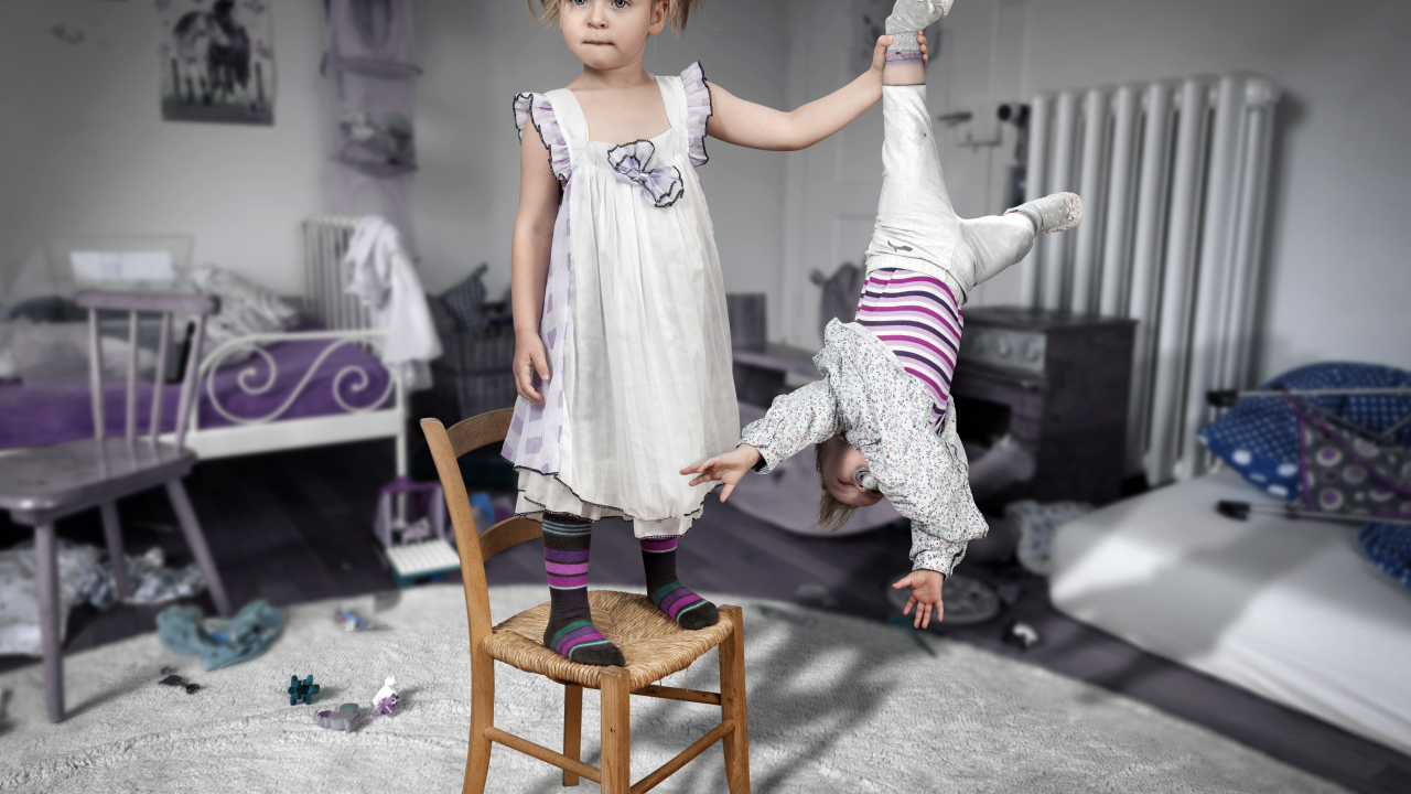 Девочка держит маленького брата за ногу